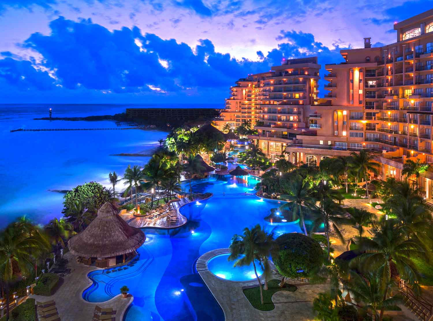 Vive la magia del Caribe al caer la noche: albercas iluminadas que serpentean entre palmeras, terrazas con vista al océano y un ambiente que combina lujo y serenidad. Nuestros paquetes exclusivos te invitan a disfrutar de Cancún como nunca antes, con experiencias diseñadas para que cada instante sea inolvidable